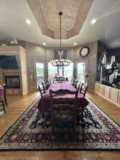 Dining area featuring a tray ceiling, an inviting chandelier, baseboards, and light wood finished floors