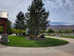 View of property's community with a mountain view, fence, and a lawn