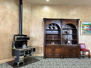 Office space featuring a wood stove, a textured wall, and baseboards