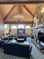 Carpeted living room featuring high vaulted ceiling, wooden ceiling, a wealth of natural light, beamed ceiling, and a notable chandelier