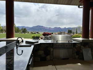 View of patio / terrace with outdoor wet bar, exterior kitchen, a sink, and a mountain view