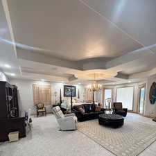 Living area with carpet floors, baseboards, and a notable chandelier