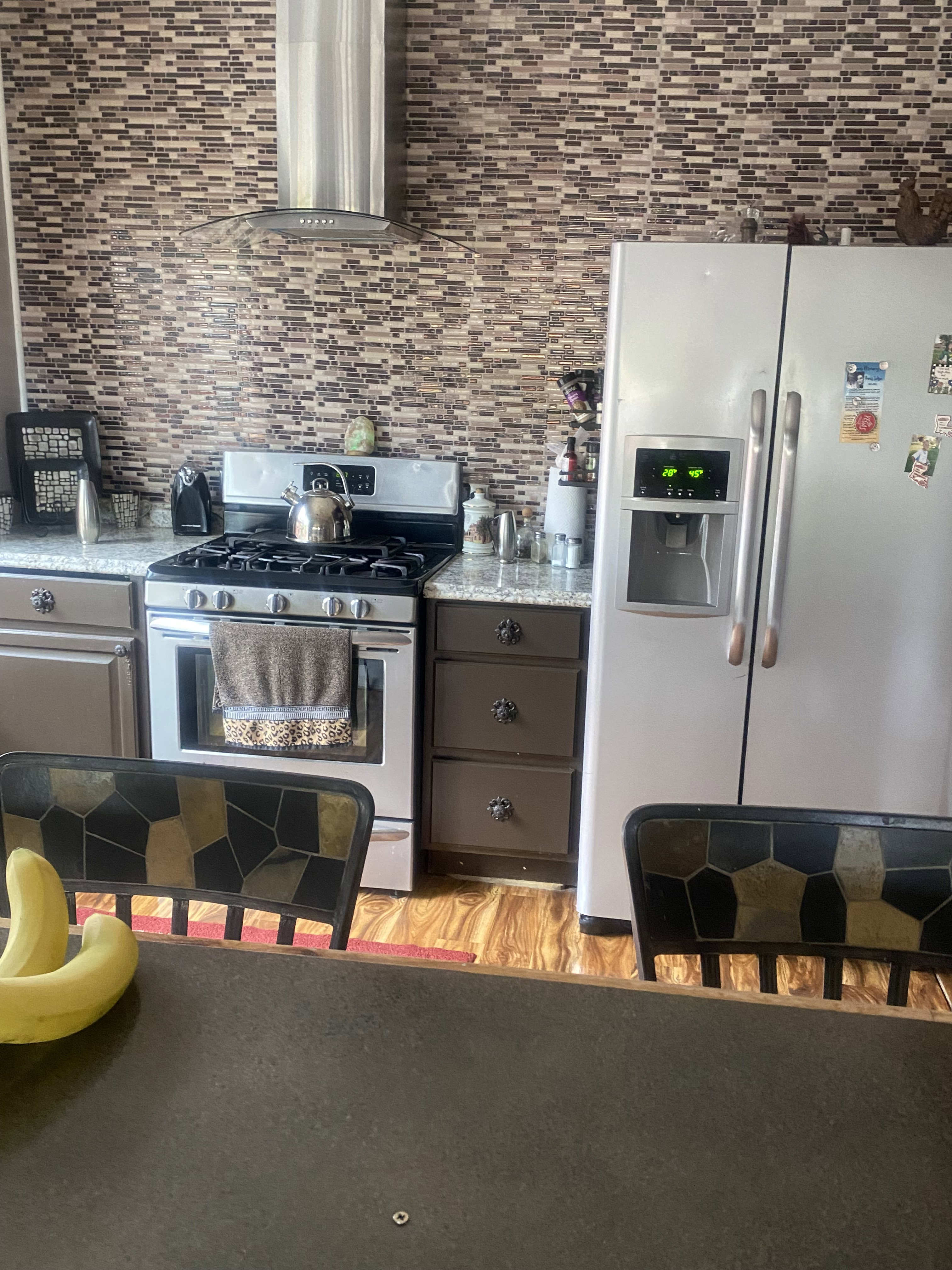 Kitchen featuring wall chimney exhaust hood, backsplash, light wood-style floors, appliances with stainless steel finishes, and gray cabinets