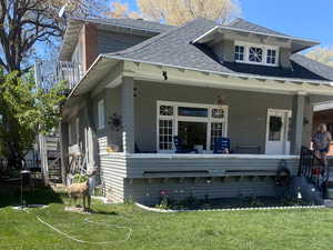 Exterior space featuring covered porch, a front yard, and a shingled roof