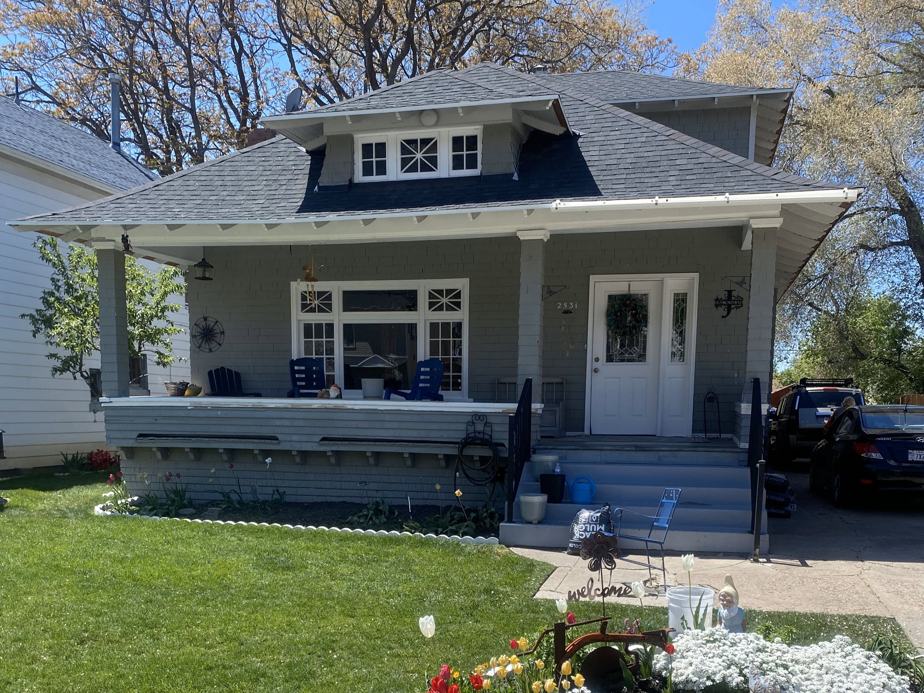 Bungalow with covered porch, roof with shingles, and a front lawn