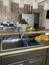 Details featuring a sink, crown molding, stainless steel appliances, and backsplash