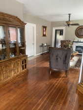 Living area featuring a glass covered fireplace, ceiling fan, a textured ceiling, and dark wood-type flooring