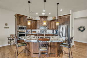 Kitchen with baseboards, a sink, an island with sink, and stainless steel appliances