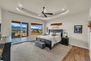 Bedroom featuring visible vents, wood finished floors, baseboards, access to outside, and a raised ceiling