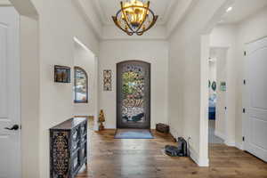 Foyer featuring an inviting chandelier, arched walkways, crown molding, and wood-type flooring