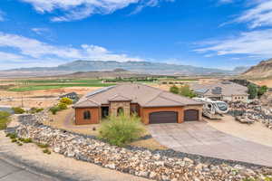 View of front of home with stucco siding, an attached garage, a mountain view, driveway, and a tile roof