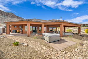 Back of property featuring a storage unit, a patio area, a hot tub, a mountain view, and a tile roof