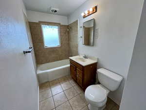 Full bath with tile patterned floors, toilet, vanity, and shower / bath combination