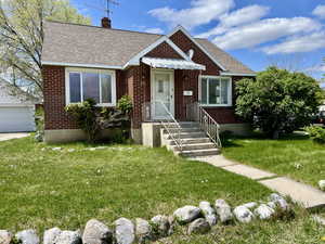 Bungalow featuring brick siding, a shingled roof, and a chimney