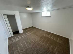 Below grade area with baseboards, dark carpet, and a textured ceiling