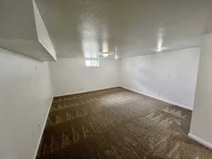 Below grade area with a textured ceiling, carpet, and baseboards