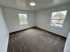 Carpeted spare room featuring a wealth of natural light, visible vents, and baseboards