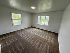 Spare room featuring carpet flooring, baseboards, and plenty of natural light