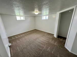 Below grade area featuring a textured ceiling, carpet flooring, and baseboards