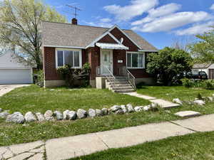 View of front of property featuring a chimney, an outbuilding, a detached garage, a shingled roof, and a front yard