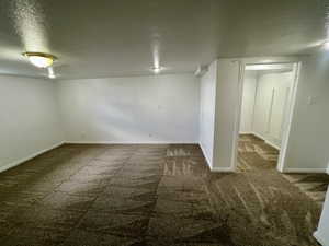 Basement with a textured ceiling, carpet floors, and baseboards