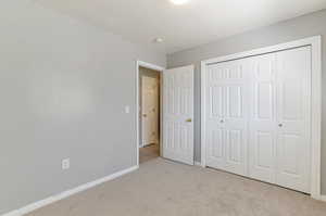 Unfurnished bedroom with light colored carpet, baseboards, and a closet