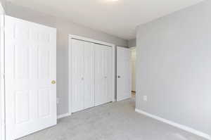 Unfurnished bedroom featuring baseboards, a closet, and carpet floors