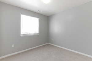 Unfurnished room featuring light colored carpet, visible vents, and baseboards