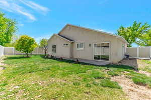 Rear view of house with a yard, a patio area, stucco siding, and a fenced backyard