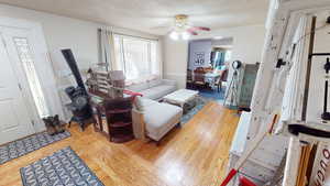 Living area featuring ceiling fan, a textured ceiling, and wood finished floors