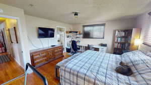 Bedroom featuring multiple windows, a textured ceiling, and wood finished floors