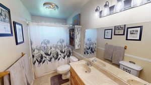 Full bath featuring tile patterned floors, toilet, a shower with shower curtain, and vanity