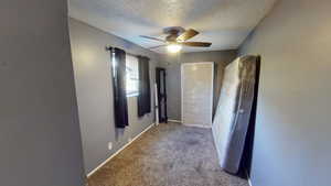 Hall with a textured ceiling, baseboards, and carpet floors
