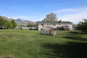 Rear view of property featuring a yard, a chimney, stairs, a trampoline, and a fenced backyard