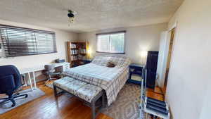 Bedroom with a textured ceiling and wood finished floors