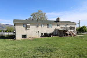 Back of property featuring a yard, brick siding, fence, stairway, and a wooden deck