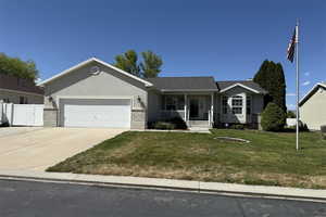Ranch-style home featuring fence, covered porch, an attached garage, concrete driveway, and a front lawn