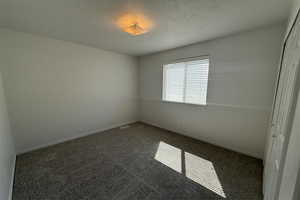 Unfurnished room with baseboards and dark colored carpet