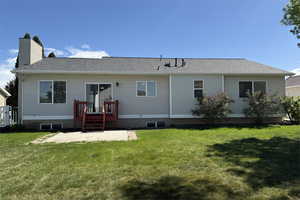 Back of house with a yard, a patio, a shingled roof, and a chimney