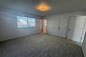 Unfurnished bedroom with carpet floors, baseboards, and visible vents