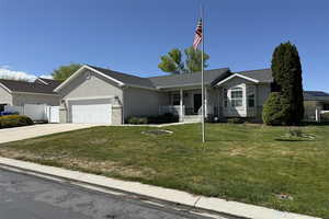 Ranch-style house featuring an attached garage, stucco siding, concrete driveway, a front yard, and a porch
