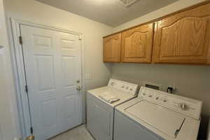 Laundry area with cabinet space, washing machine and dryer, visible vents, and marble finish floor