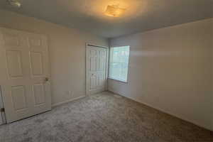 Unfurnished bedroom featuring baseboards, carpet flooring, a closet, and a textured ceiling