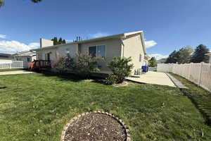 Back of house with a patio, a wooden deck, a lawn, and a fenced backyard