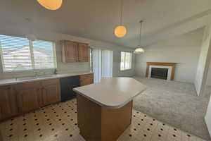 Kitchen featuring a sink, lofted ceiling, black dishwasher, light countertops, and a center island