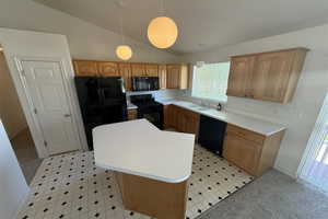 Kitchen with a sink, light floors, black appliances, vaulted ceiling, and a kitchen island