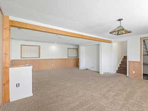 Finished basement with stairway, wood walls, wainscoting, and carpet floors