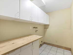 Washroom featuring light tile patterned floors, electric dryer hookup, cabinet space, washer hookup, and baseboards