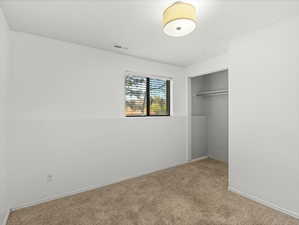 Unfurnished bedroom featuring a closet, visible vents, baseboards, and carpet floors