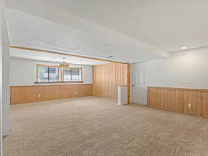 Carpeted spare room featuring wood walls and a wainscoted wall